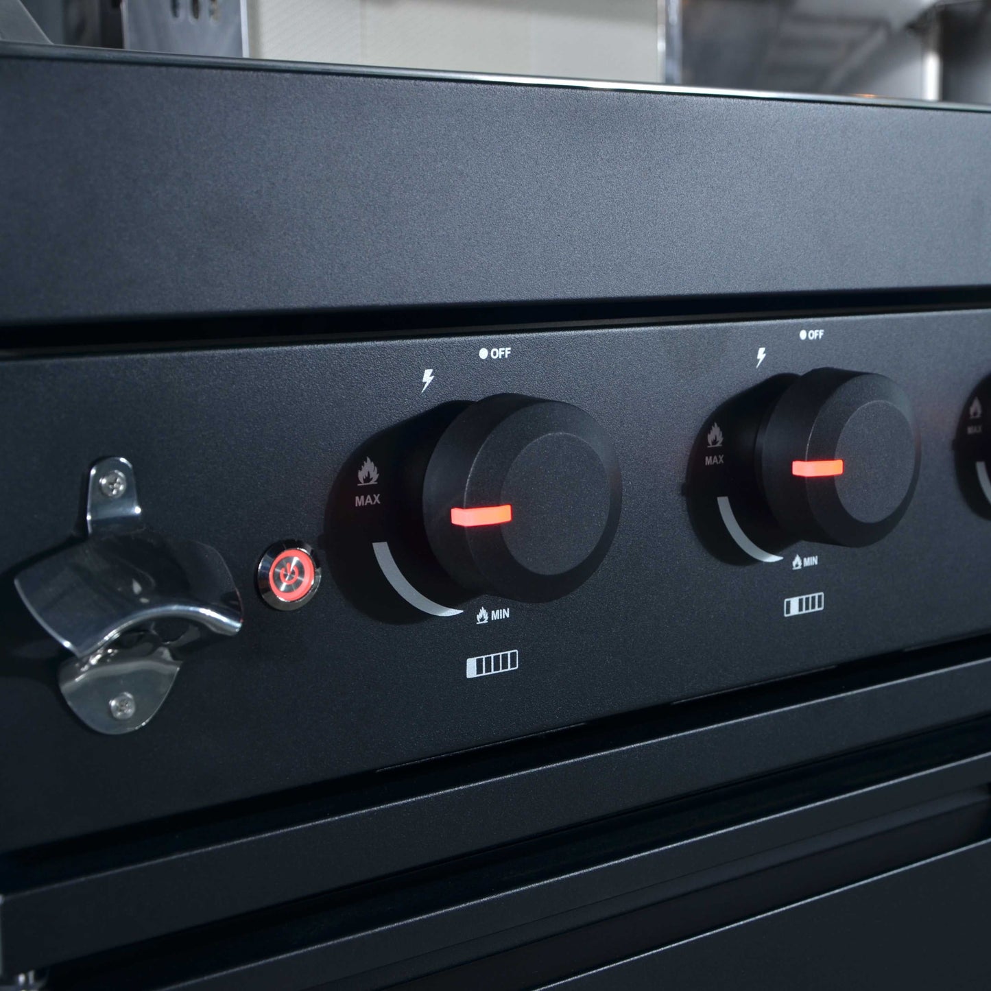 Black stove with control knobs and a bottle opener on a metallic surface