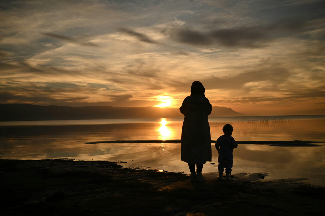 Mother and child silhouetted at sunset by a lakeshore. Photograph: Esra Betül Yatkaya.